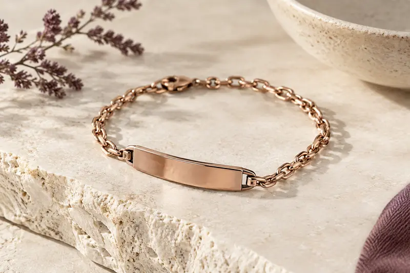 Bracelet gravé posé sur une pierre claire, plaque métallique mise en évidence