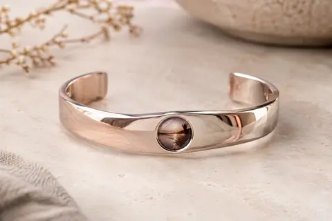 Bracelet Avinvan argenté avec pierre de projection intérieure, posé en gros plan sur une pierre claire.