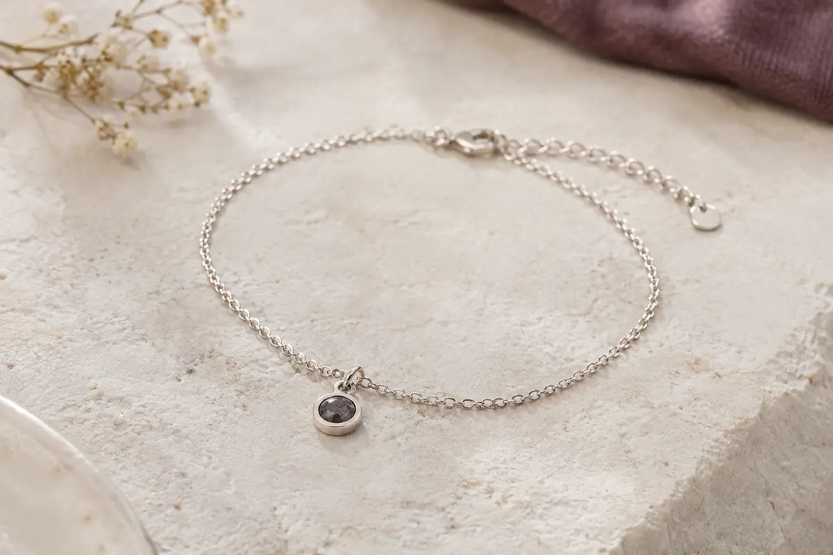 Bracelet photo en argent 925 avec pendentif de projection, posé seul sur une surface de pierre claire.