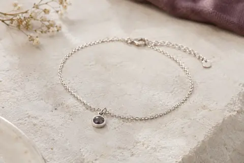 Bracelet photo en argent 925 avec pendentif de projection, posé seul sur une surface de pierre claire.
